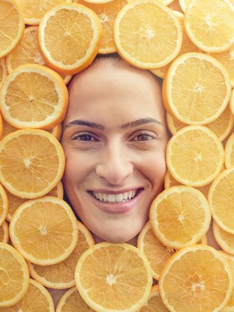 Smiling woman among slices of ripe oranges