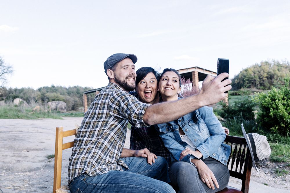 Three people sitting outdoors and taking a selfie