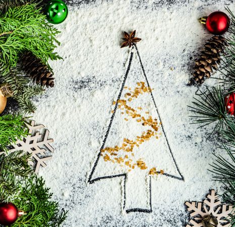 Baking concept of Christmas tree outline in flour with tinsel brown sugar
