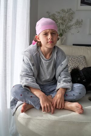 Boy in pink scarf frowning face sitting near dog