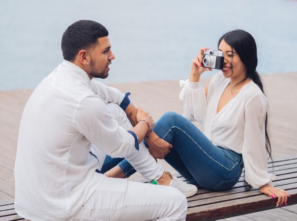 Woman taking photo and sitting with man on bench