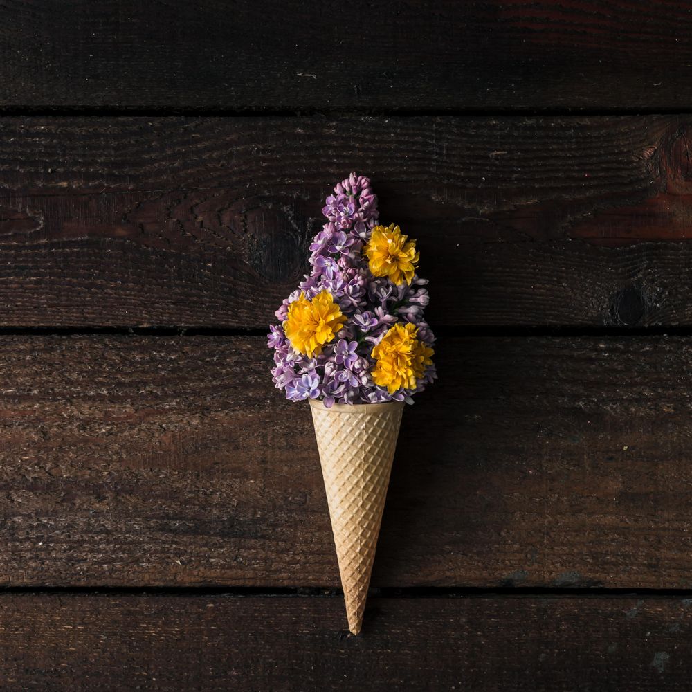 Ice cream cone with purple lilac on wooden background