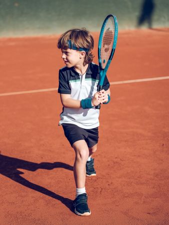 Preteen boy preparing for stroke with tennis racket