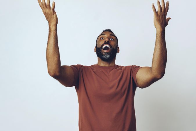 Joyful man with open mouth smile and arms up