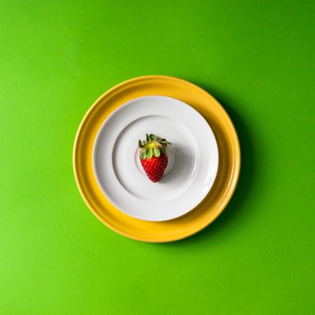 Strawberry on plate setup on green background