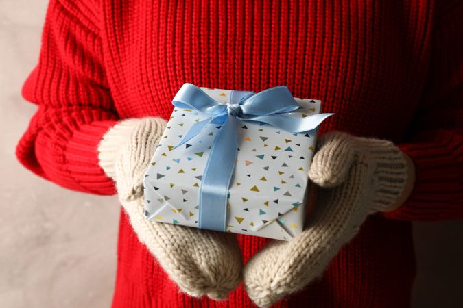 Young woman holding gift box with light blue bow, close up