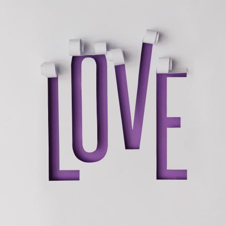 Word LOVE made of torn paper on violet background