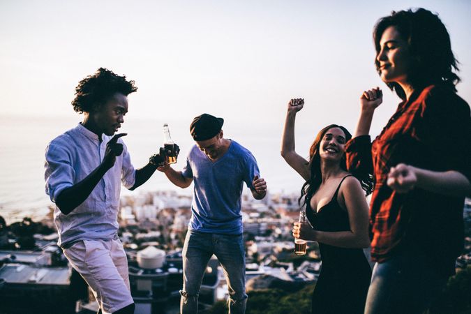 Group of friends dancing out outside with city and ocean in the background