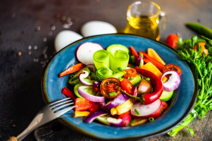 Colorful healthy raw vegetable salad served on blue plate