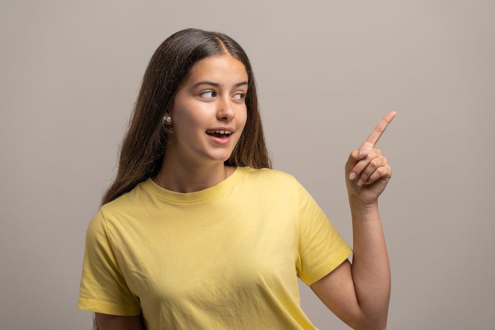 Surprised young woman pointing and looking at something with an amazed expression.