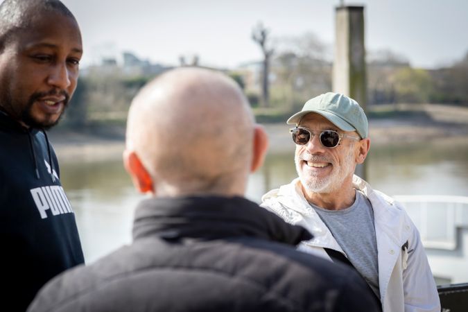 Older male friends chatting together over river