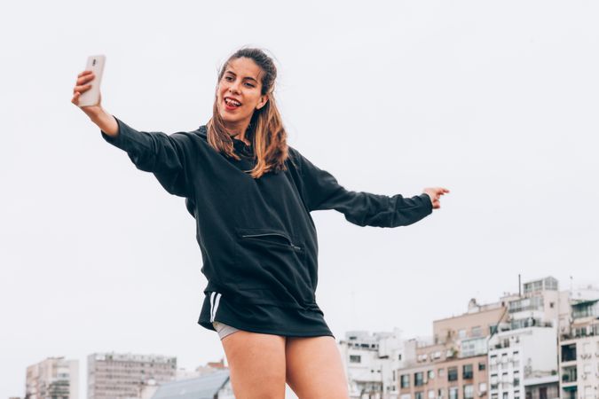 Content young woman in casual wear taking selfie at city street
