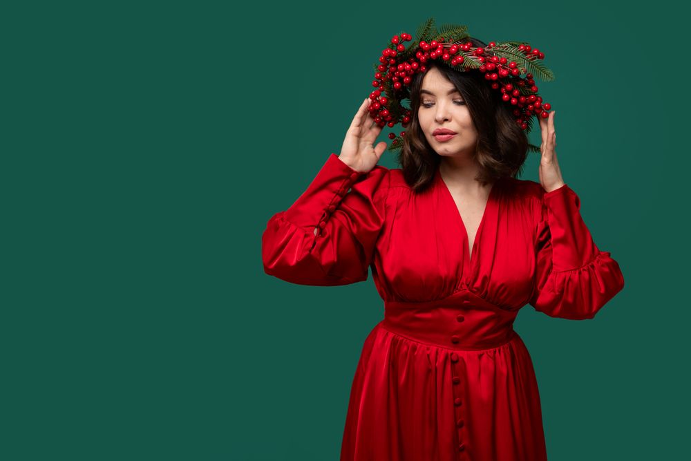 Woman in red dress with berry wreath posing elegantly