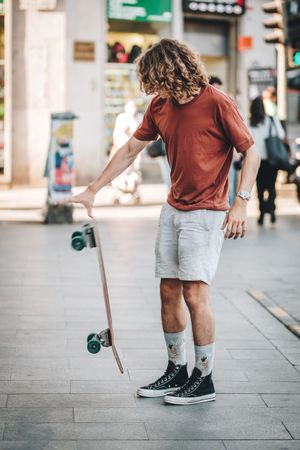 Confident man riding longboard across city street