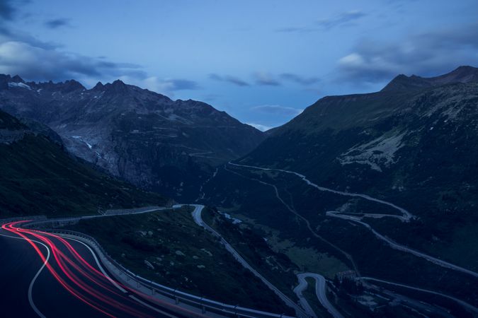 Car lights of driving cars on road curving in mountains