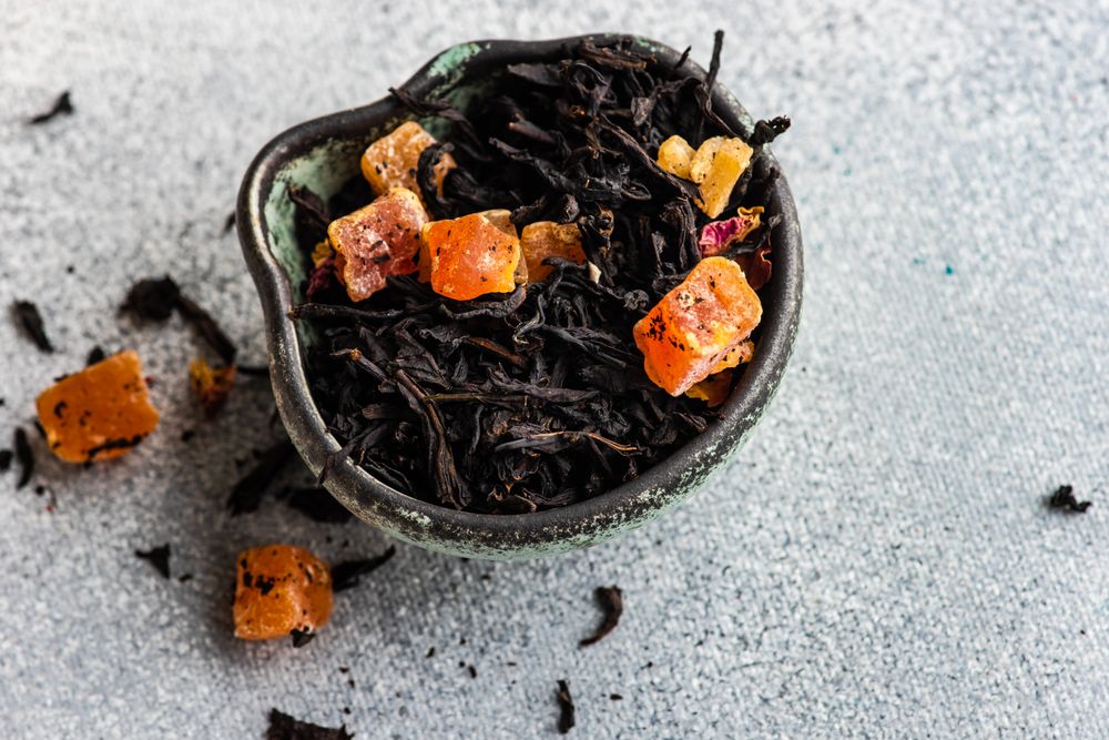 Papaya loose leaf tea in bowl on stone background