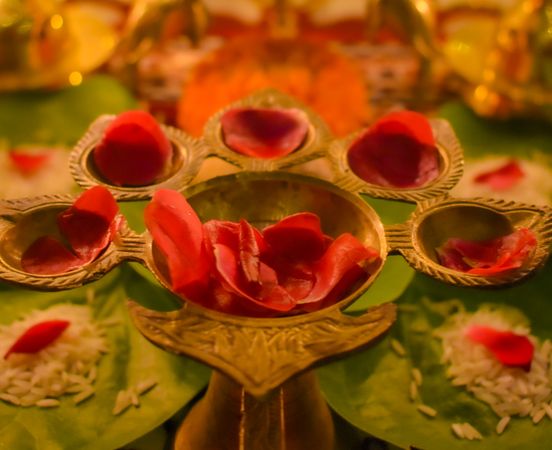 Rose petals on golden panch aarti on a table in close-up