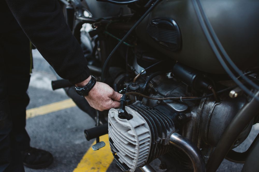 Crop man repairing motorcycle engine