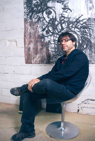 Painter artist posing in front of modern artwork