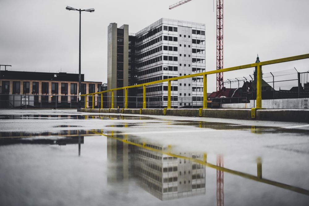 Skyscraper reflecting in puddle on street floor