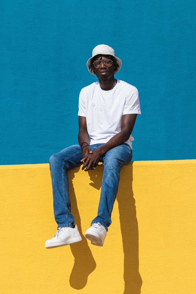Happy Black man sitting on colorful wall
