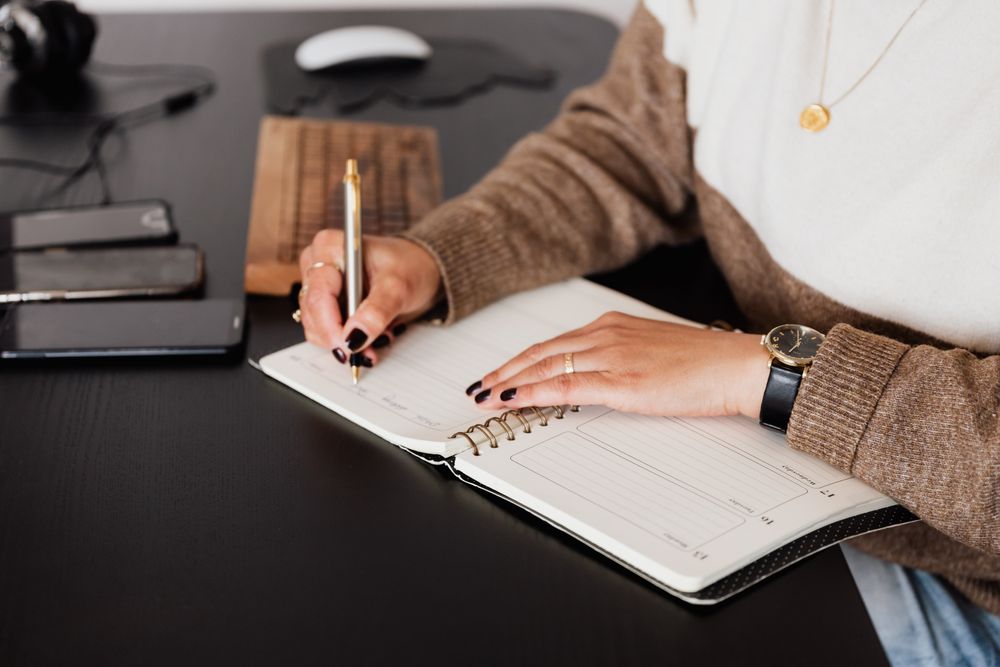 Woman writing a note beside computer keyboard