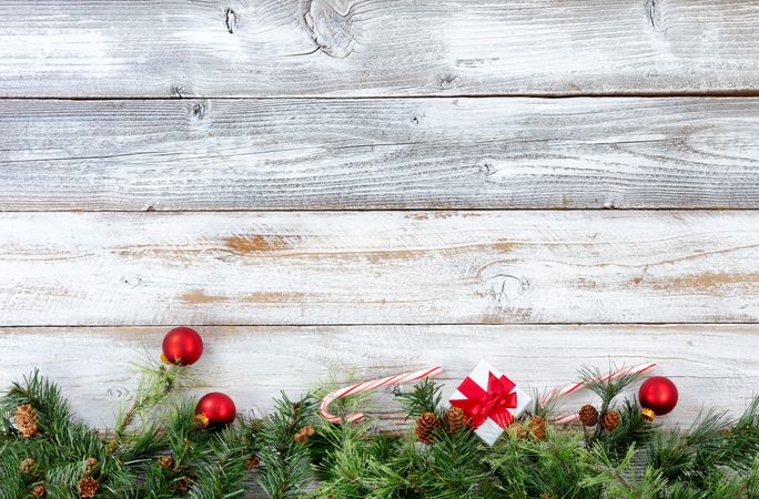 Bottom border of Christmas evergreen branches with other holiday decorations on rustic wood