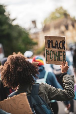 Person holding brown sign saying "Black Power"