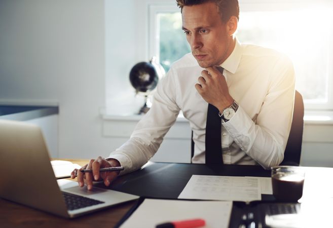Man in shirt and tie on laptop in office