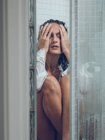 Sorrow woman sitting on floor of shower cabin