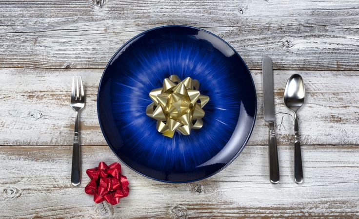 Winter holiday table setting with vintage cutlery, empty blue plate, fork, spoon and knife on rustic wood table
