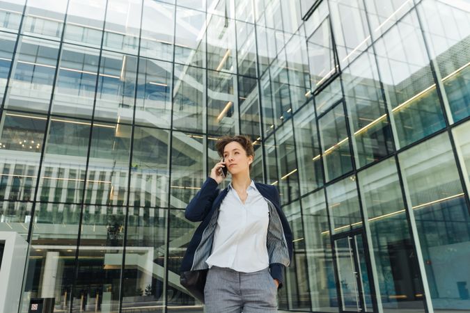 Smiling entrepreneur browsing smartphone outside office building