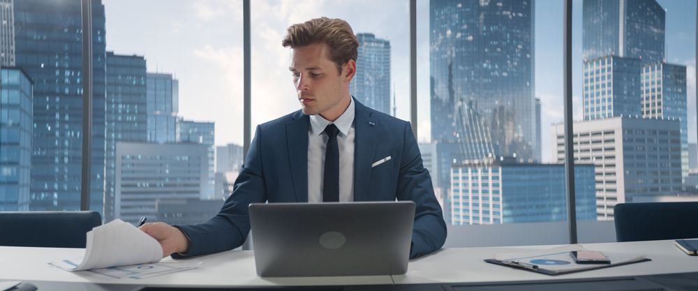 Confident Businessman in a Suit Sitting at a Desk in Office