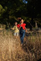 Sister and brother walking in grassy meadow