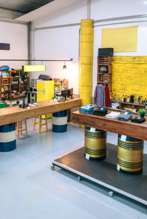 Interior of empty clothing store with clothes on counter over fuel barrels and industrial style