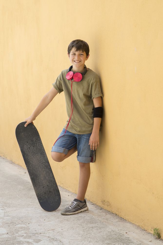 A Teen with skateboard standing on city street