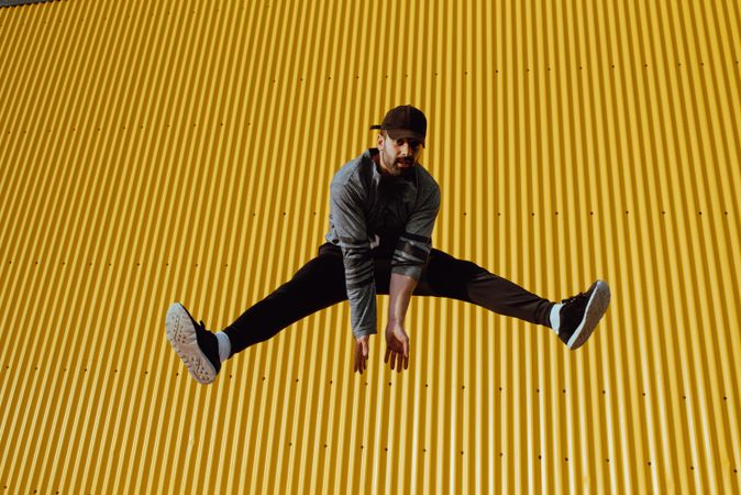 Man jumping near yellow wall