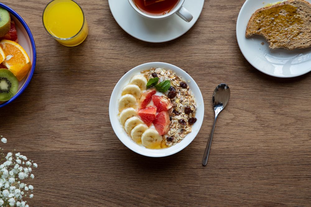Juice and plate with granola and fruits on table