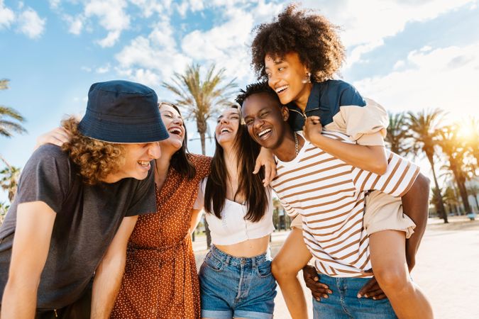 Laughing multi-ethnic friends with one couple piggybacking