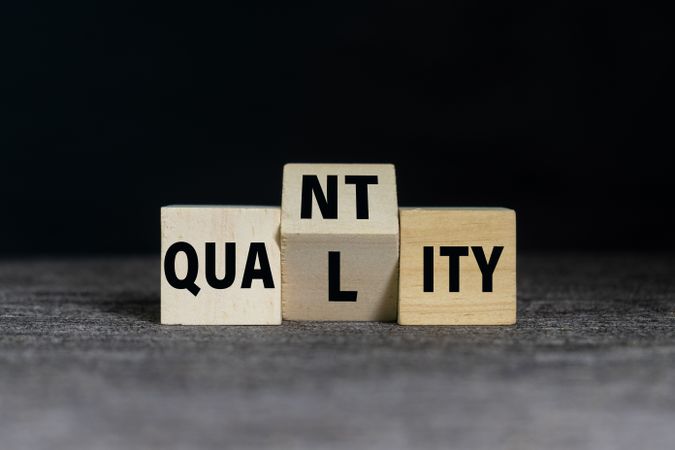 flip wooden blocks with quality and quantity words on dark background