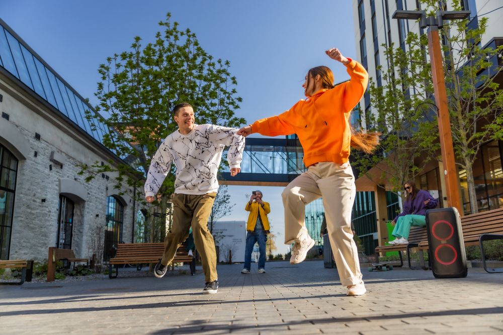 Vibrant Outdoor Scene Capturing Two Young Adults Joyfully Dancing In A Sunny