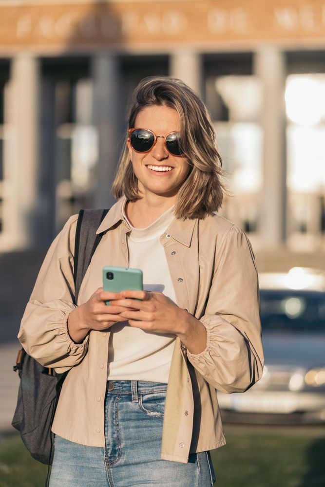 student watching mobile in college. Blonde girl
