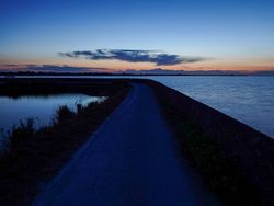 Sunrise illuminating the path of the dike at high tide