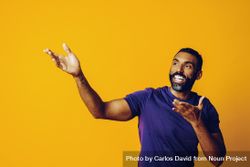 Black man smiling in yellow studio with hands up to the side 0VkLr5