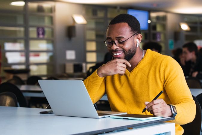 Smiling Black man working on laptop with tablet