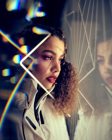 Young woman looking at her reflection surrounded by camera flares