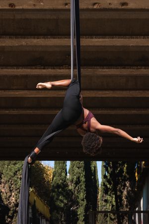 Slim woman doing aerial yoga in city