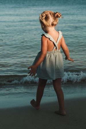 Anonymous girl walking on seashore in dusk
