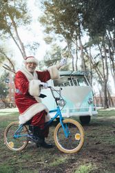 Happy Santa Claus riding bicycle by van