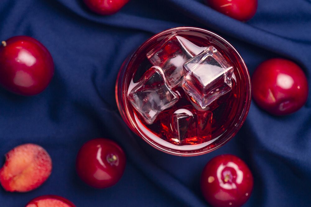 Red beverage near fresh fruits on cloth